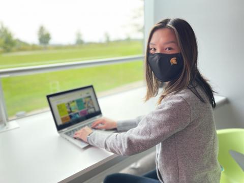 Student wearing a UW mask on a laptop